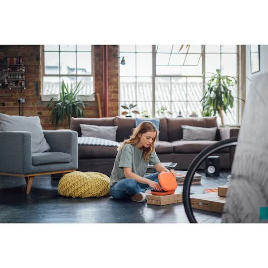 Mujer ensamblando mueble en sala de estar iluminada.