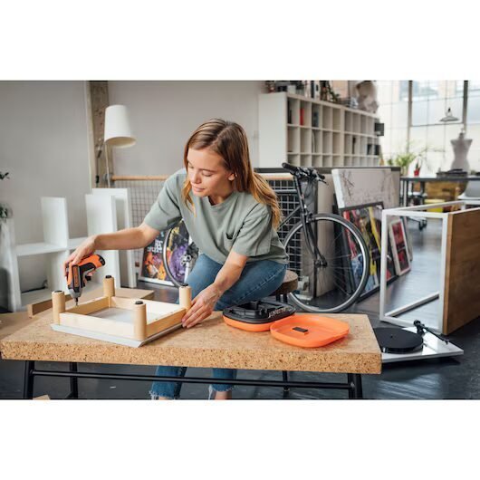 Mujer ensamblando mesa con taladro en taller moderno.