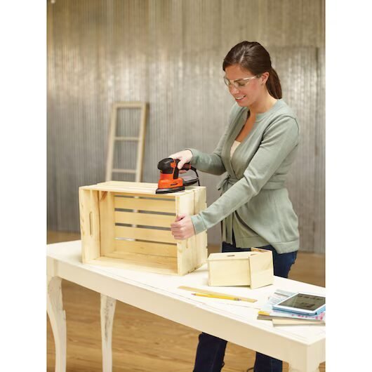 Mujer lijando caja de madera en taller de bricolaje.