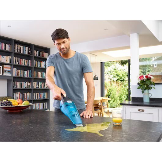 WDC215WA_A2.jpg Hombre limpiando derrame en cocina con aspiradora portátil.
