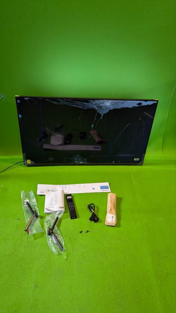 Televisor roto con accesorios y manual en el suelo.