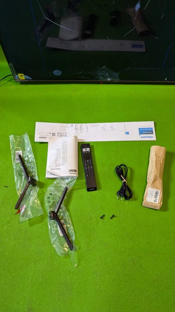 Partes de un televisor Philips sobre alfombra verde.