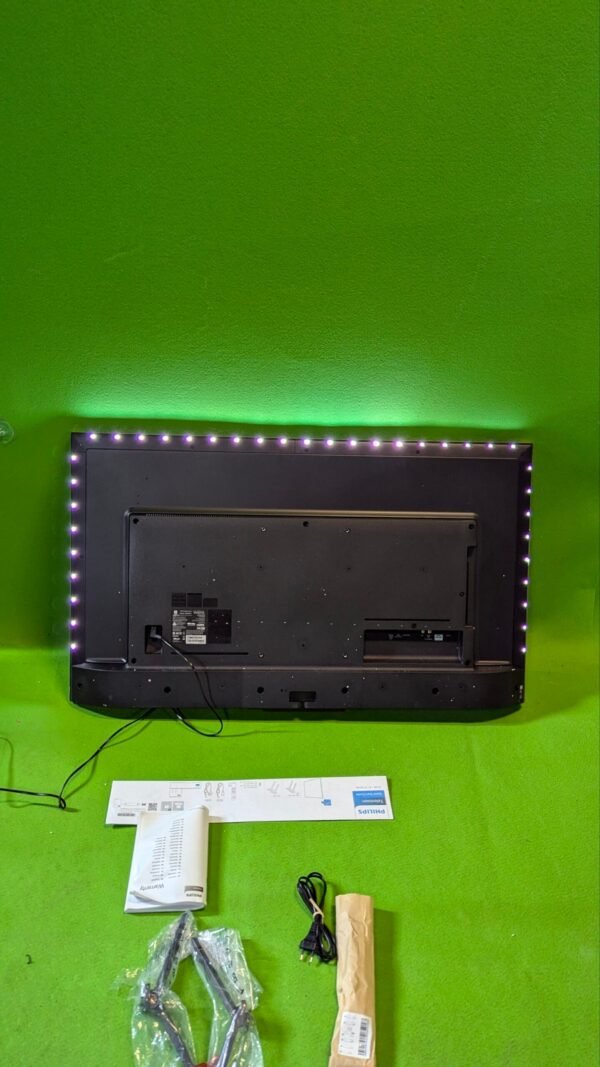 Monitor con luz LED y accesorios sobre alfombra verde.