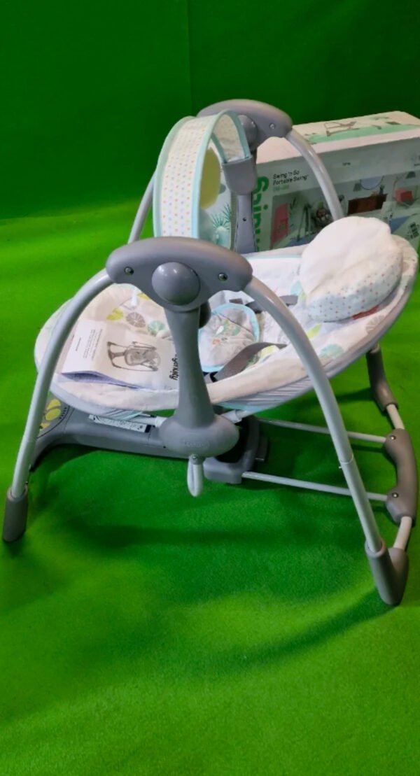 Columpio de bebé portátil en alfombra verde.