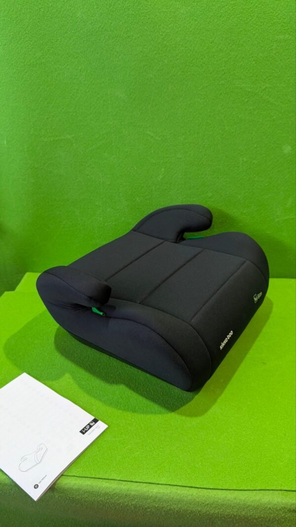 Asiento elevador negro sobre fondo verde con manual.