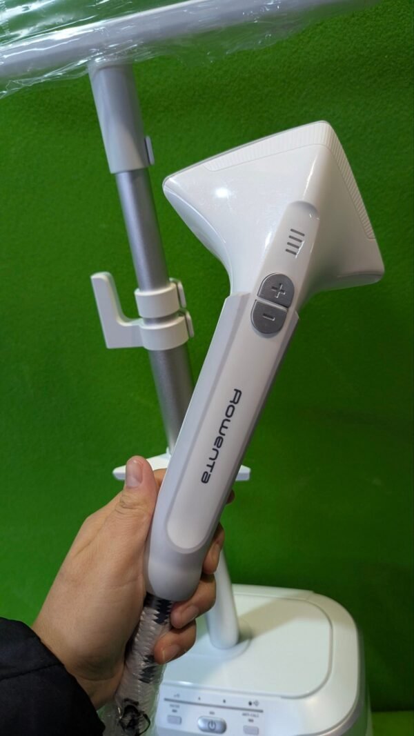 1000092514-scaled-1.jpg Vaporizador de prendas Rowenta en mano, fondo verde.