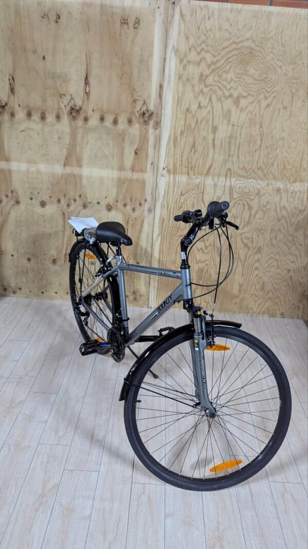 Bicicleta gris en interior sobre suelo de madera.