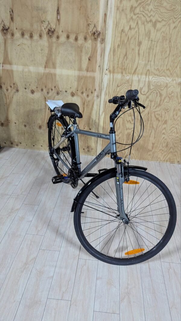 Bicicleta gris en interior sobre suelo de madera.