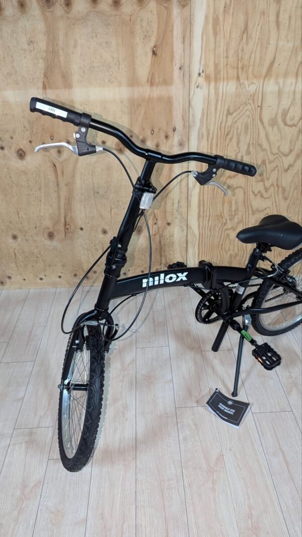 Bicicleta plegable negra sobre suelo de madera.