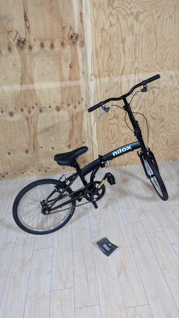 Bicicleta plegable negra sobre suelo de madera clara.