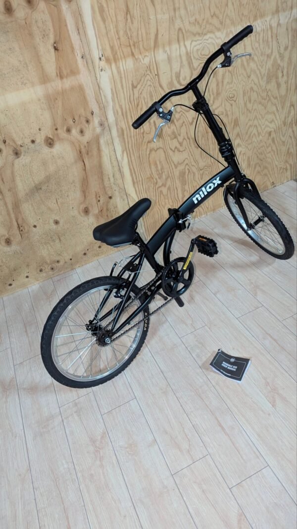 Bicicleta plegable Nilox en el suelo de madera.