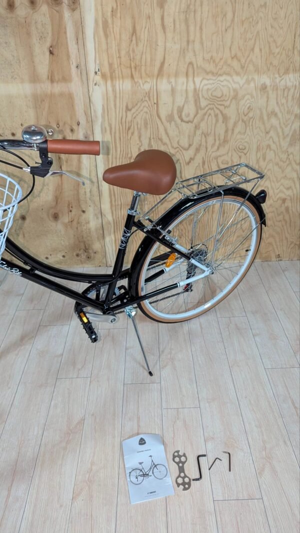 Bicicleta con cesta, instrucciones y herramientas en el suelo.