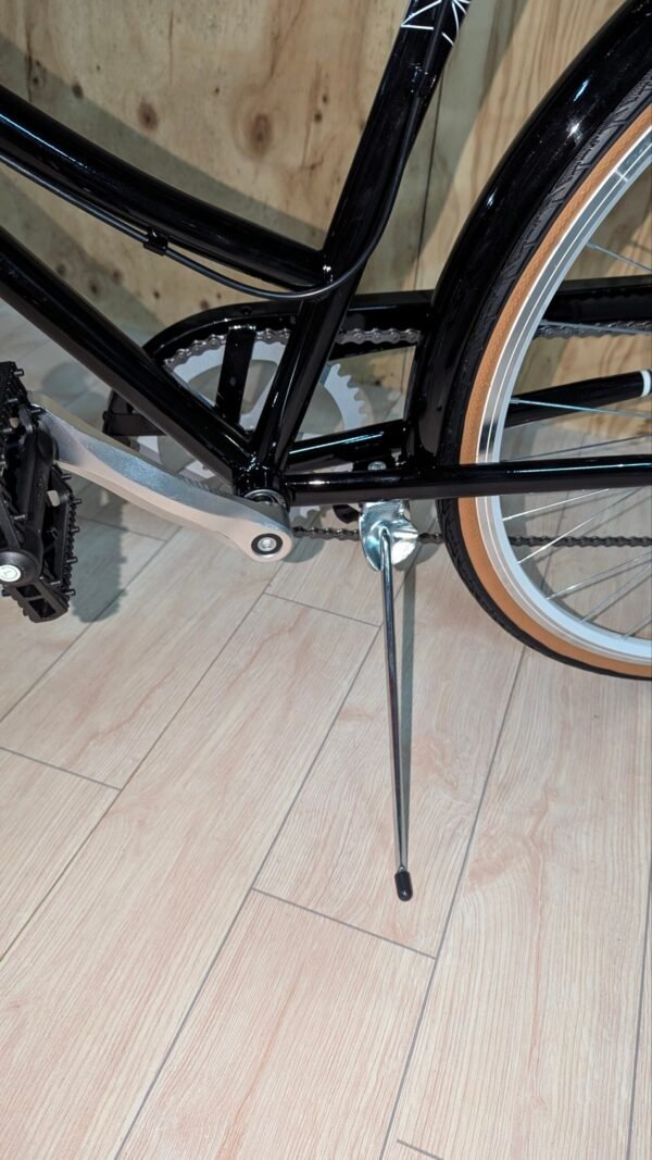 Bicicleta negra con pata de cabra en suelo de madera.