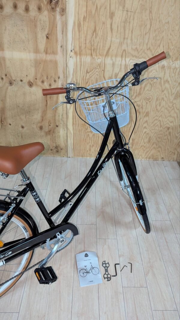 Bicicleta negra con cesta y manual en el suelo.