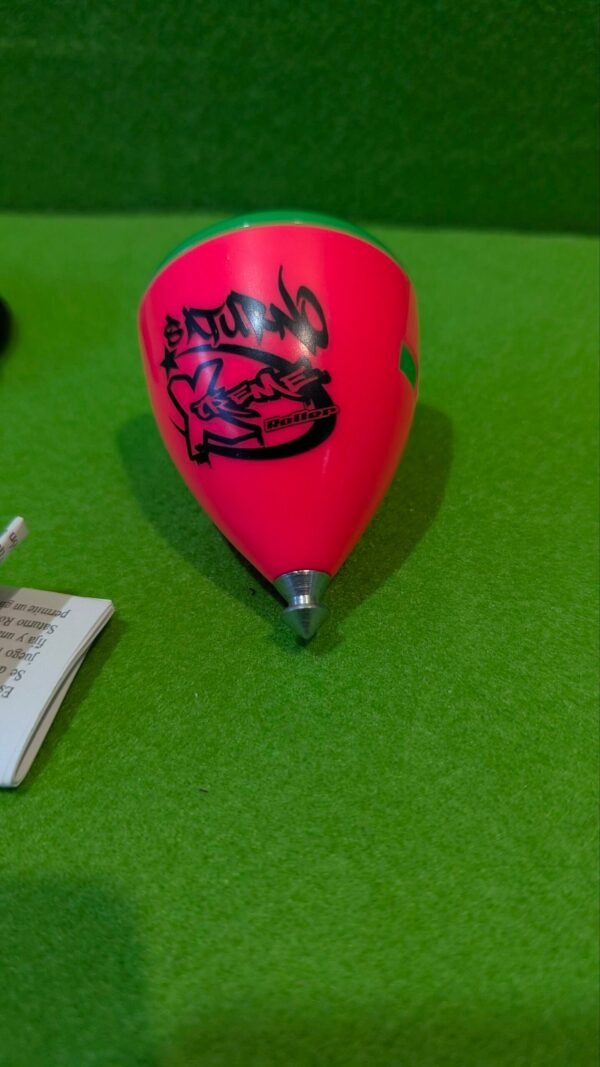 Peonza rosa Saturno sobre superficie verde