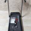 Cinta de correr plegable con accesorios sobre superficie gris.