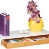 Estante blanco con libros, florero y gafas.