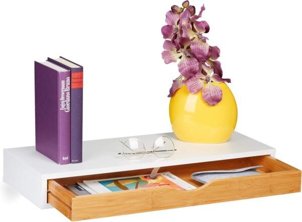 Estante blanco con libros, florero y gafas.