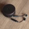 Auriculares negros con estuche en mesa de madera.