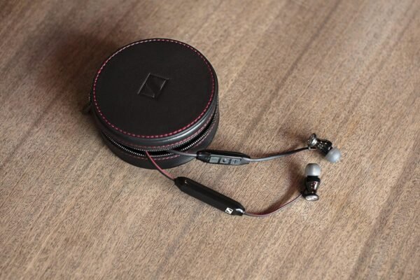 Auriculares negros con estuche en mesa de madera.