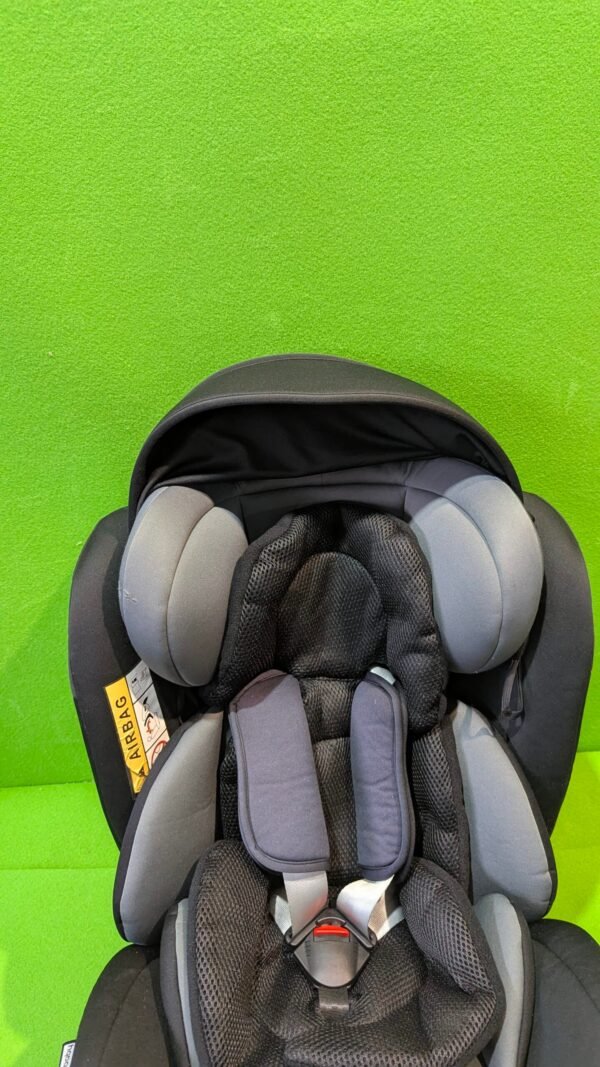 Silla de coche infantil en fondo verde vivo.