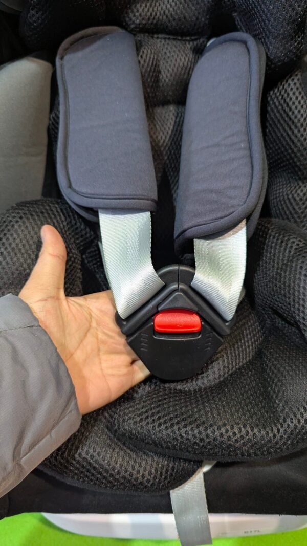 Cinturón de seguridad infantil negro con hebilla roja.