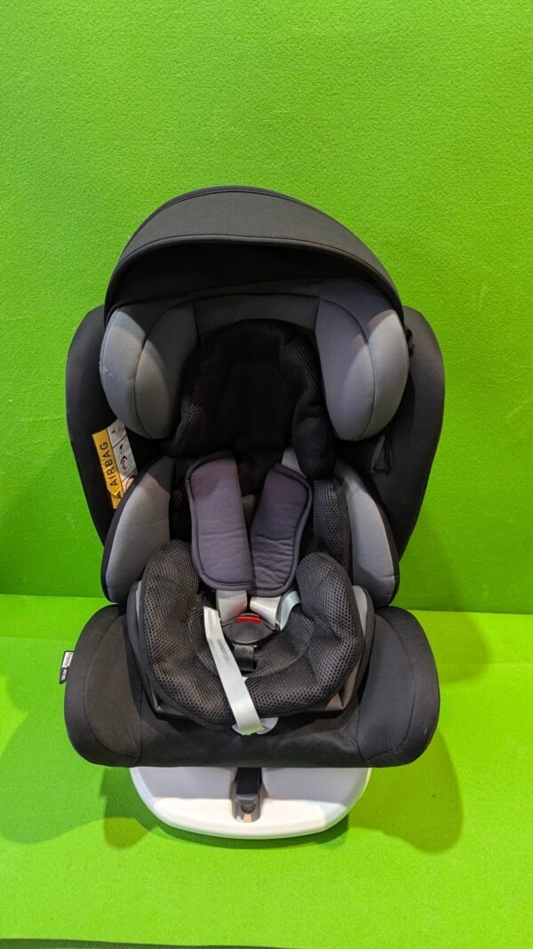Silla de coche infantil negra en fondo verde.