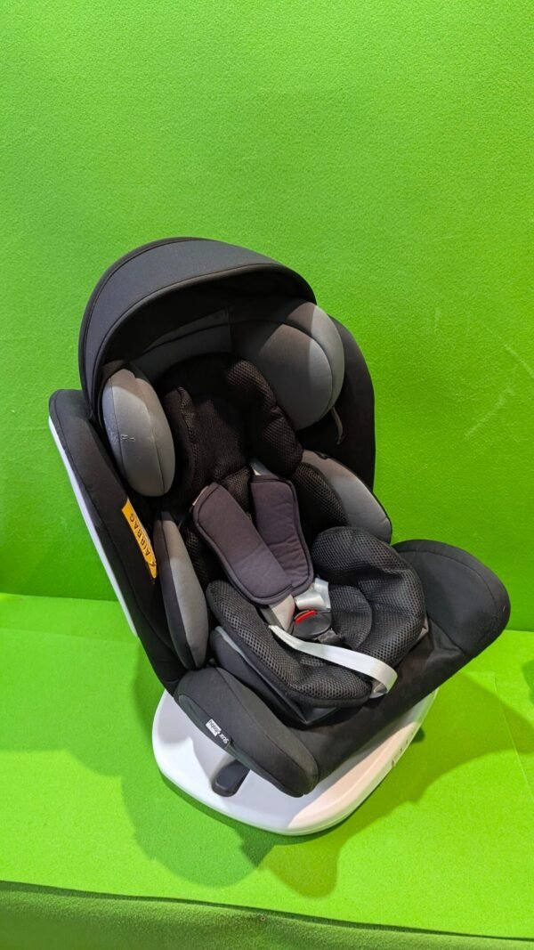 Silla de coche infantil negra sobre fondo verde.