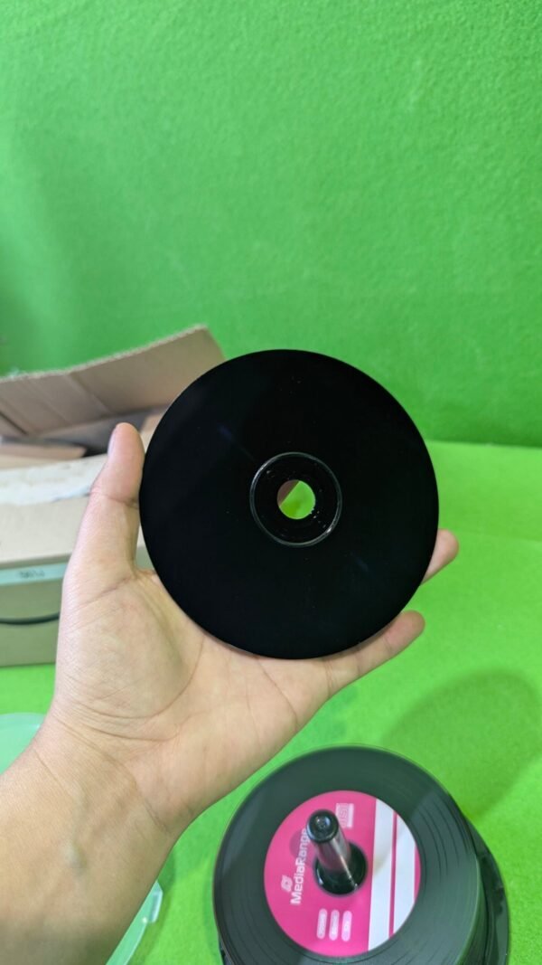 Mano sosteniendo un disco negro sobre fondo verde.