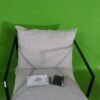 Silla moderna gris con cojín en fondo verde.