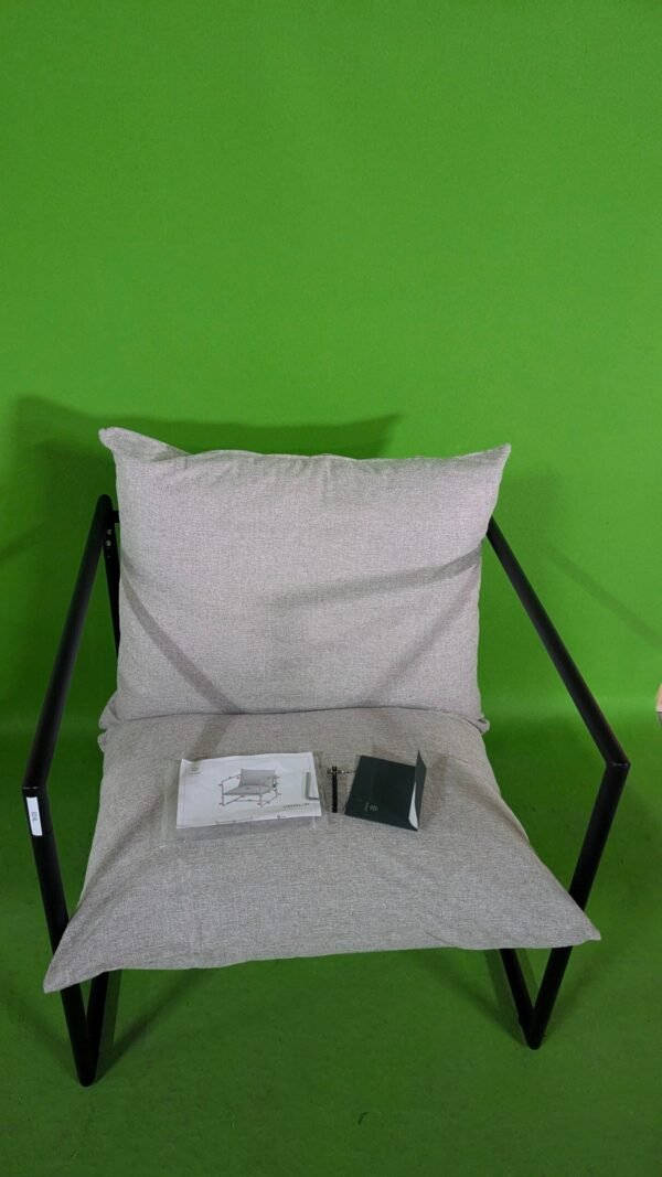 Silla moderna gris con cojín en fondo verde.