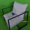 Sillón moderno con cojín sobre fondo verde.