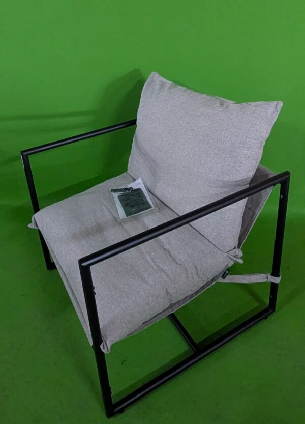 Sillón moderno con cojín sobre fondo verde.