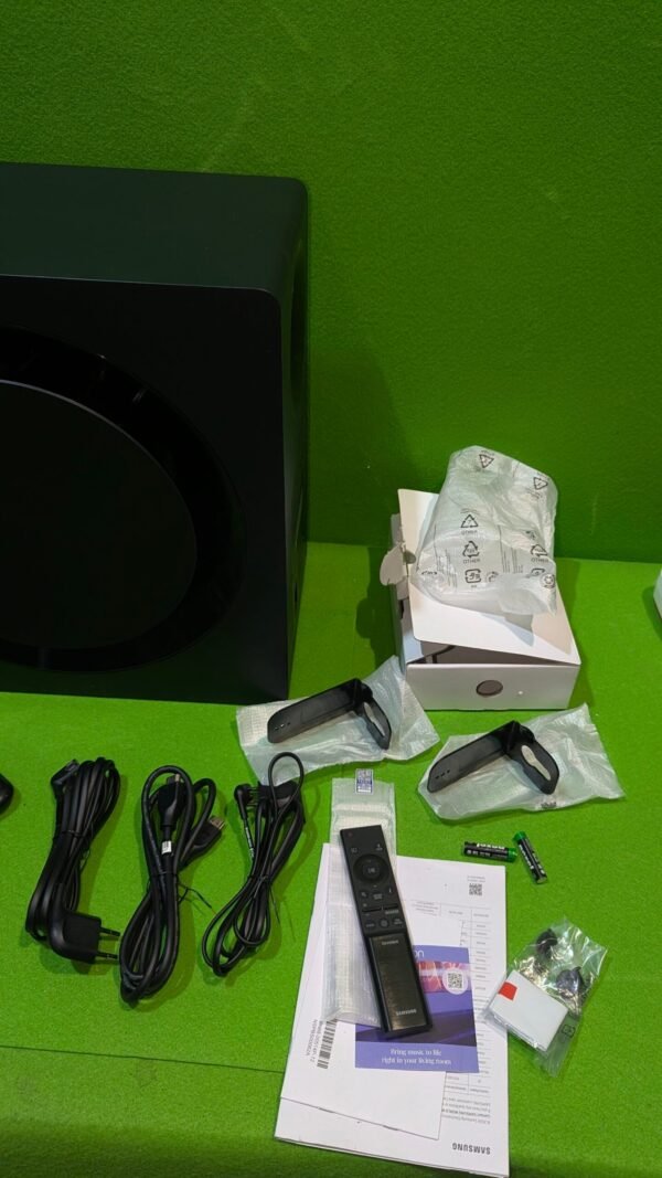 Componentes y mando de altavoz Samsung sobre mesa verde.