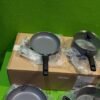 Sartenes y ollas sobre caja marrón en exposición.