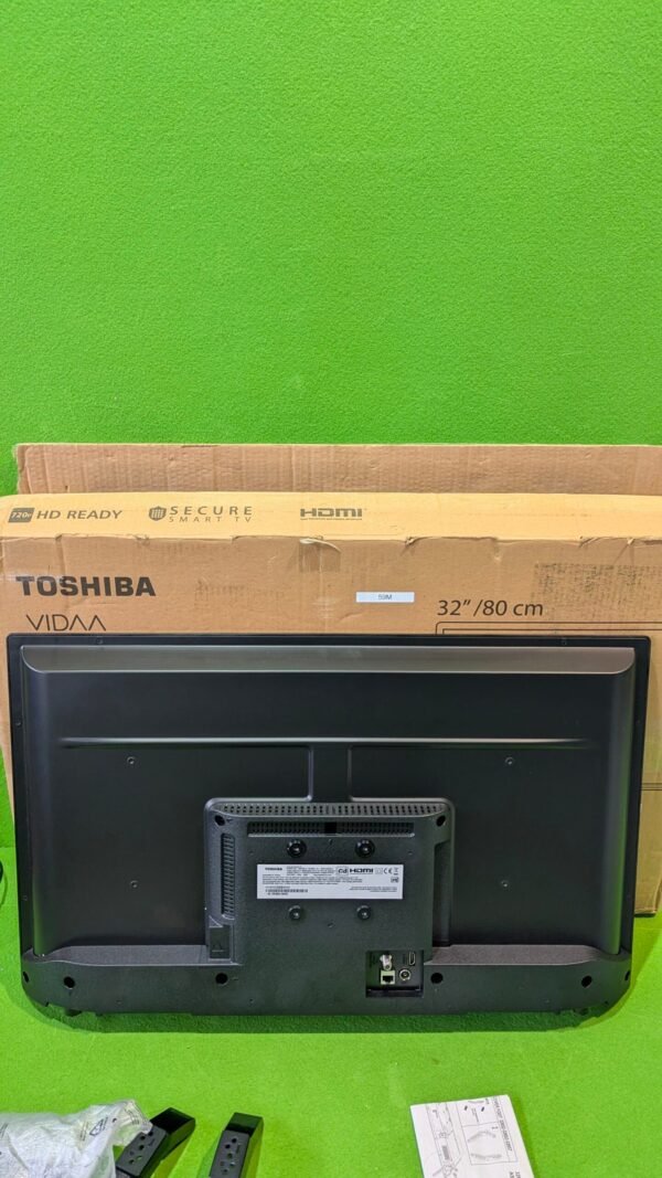 Televisión Toshiba con caja y cables sobre césped verde.