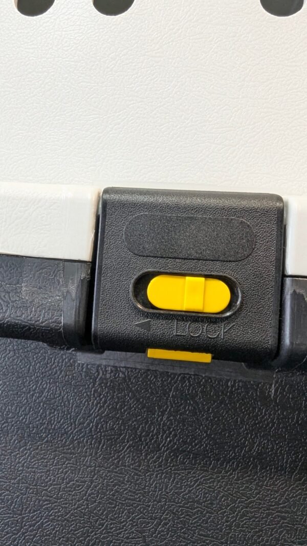 Cerradura plástica negra con botón amarillo deslizante.