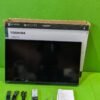 Televisor Toshiba con accesorios sobre mesa verde.