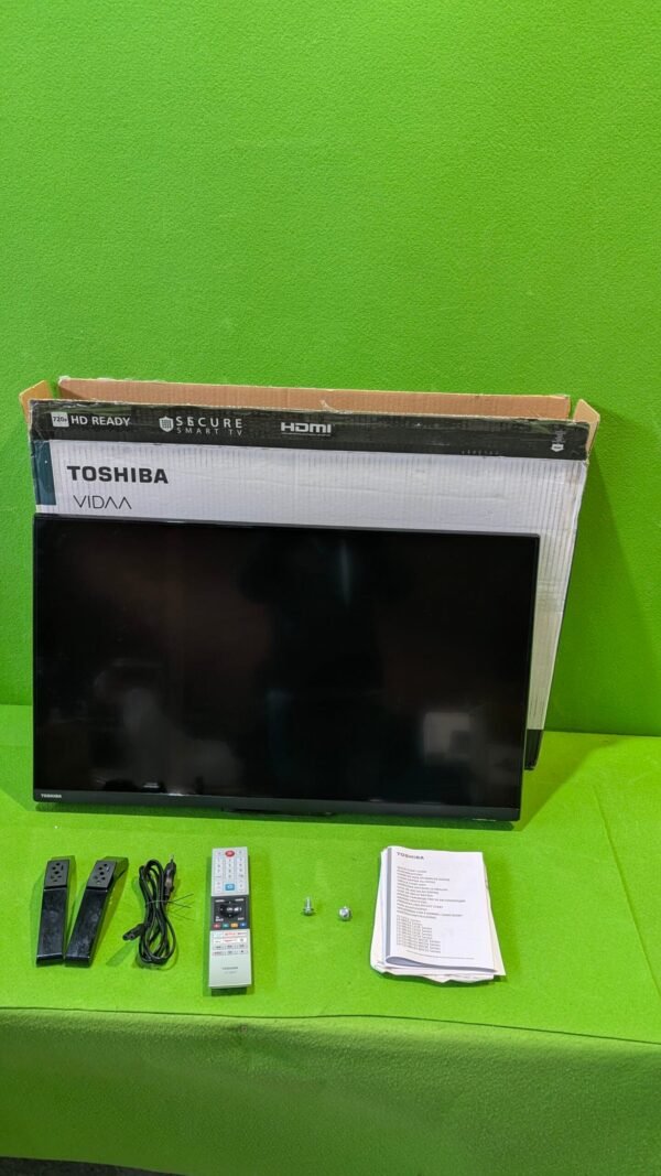 Televisor Toshiba con accesorios sobre mesa verde.