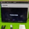 TV Toshiba con accesorios y manual en mesa verde.