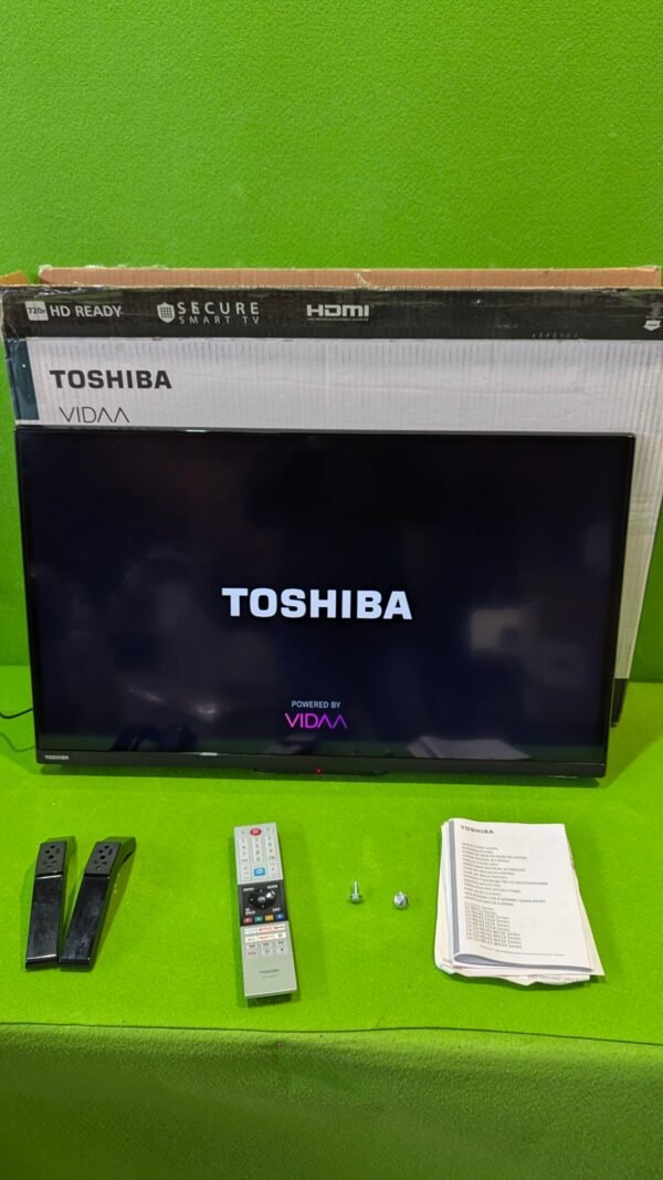 TV Toshiba con accesorios y manual en mesa verde.