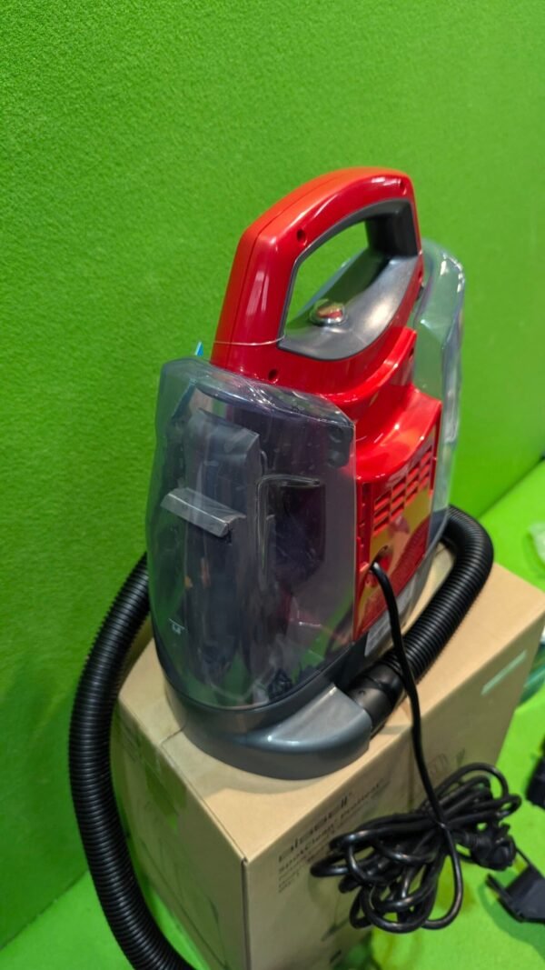 Aspiradora compacta roja sobre caja de cartón.