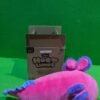 Peluche rosa junto a caja sobre fondo verde.