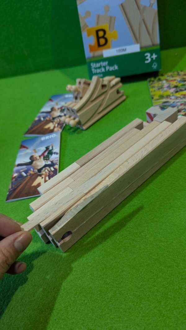 PXL_20251120_120348656.MP_-scaled-1.jpg Piezas de madera para juego infantil en mesa verde.