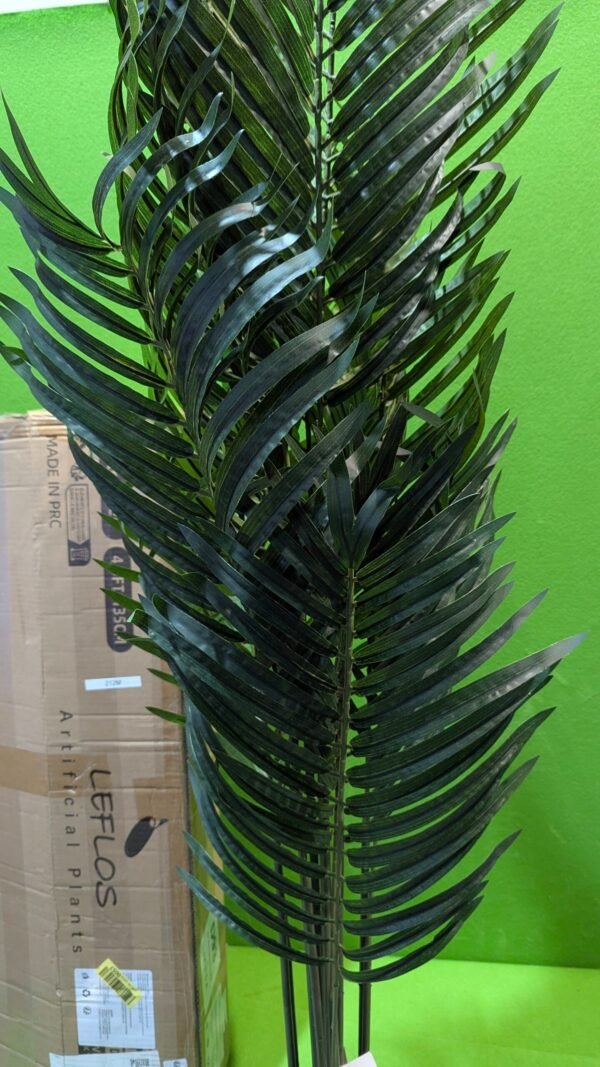 Planta artificial alta con hojas verdes brillantes.