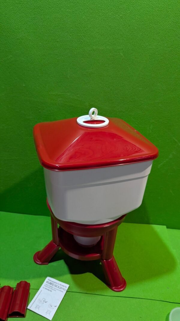 Dispensador de agua rojo y blanco sobre fondo verde.