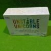 PXL_20251211_185449937-scaled-1.jpg Caja del juego Unstable Unicorns en mesa verde.