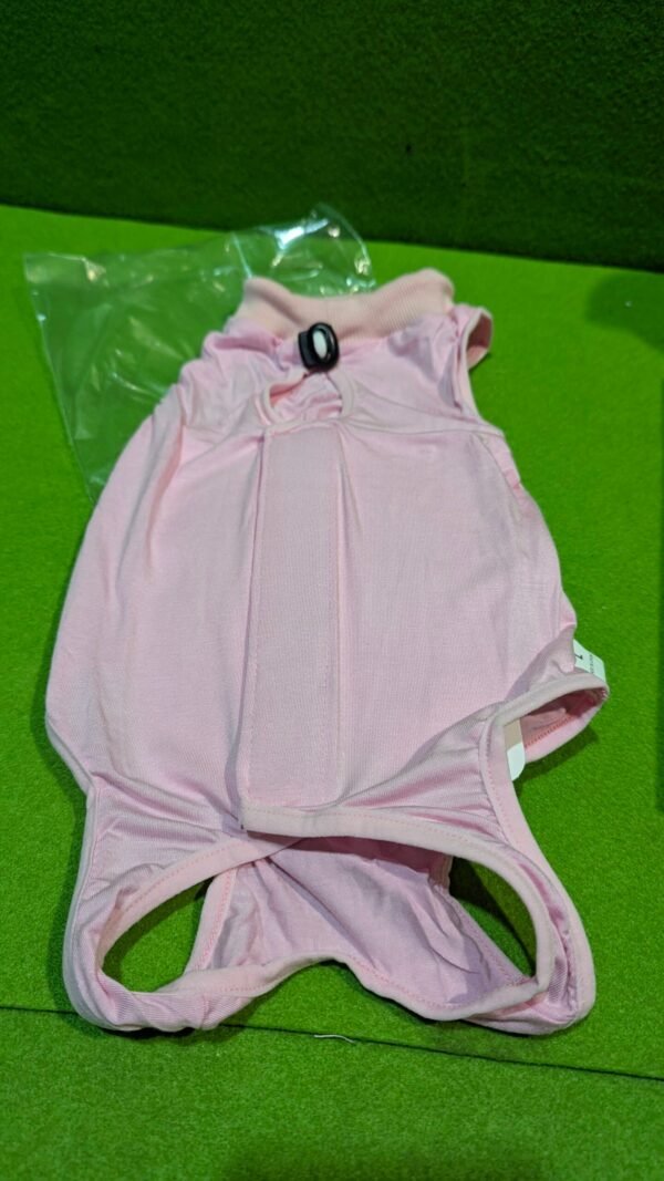 Camiseta rosa para perro sobre césped verde