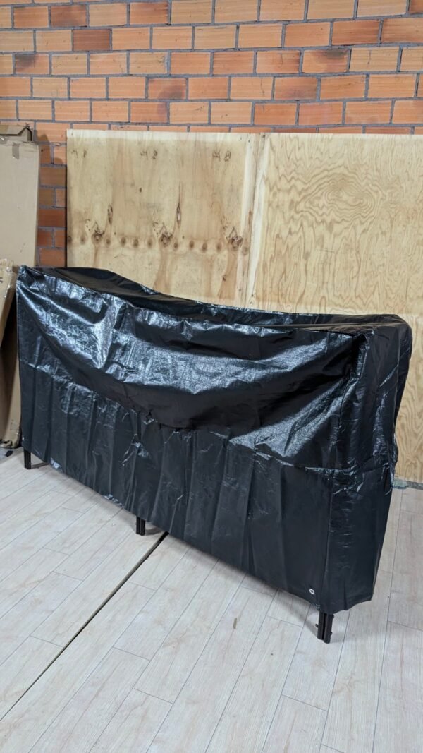 Mueble cubierto con plástico negro en garaje.