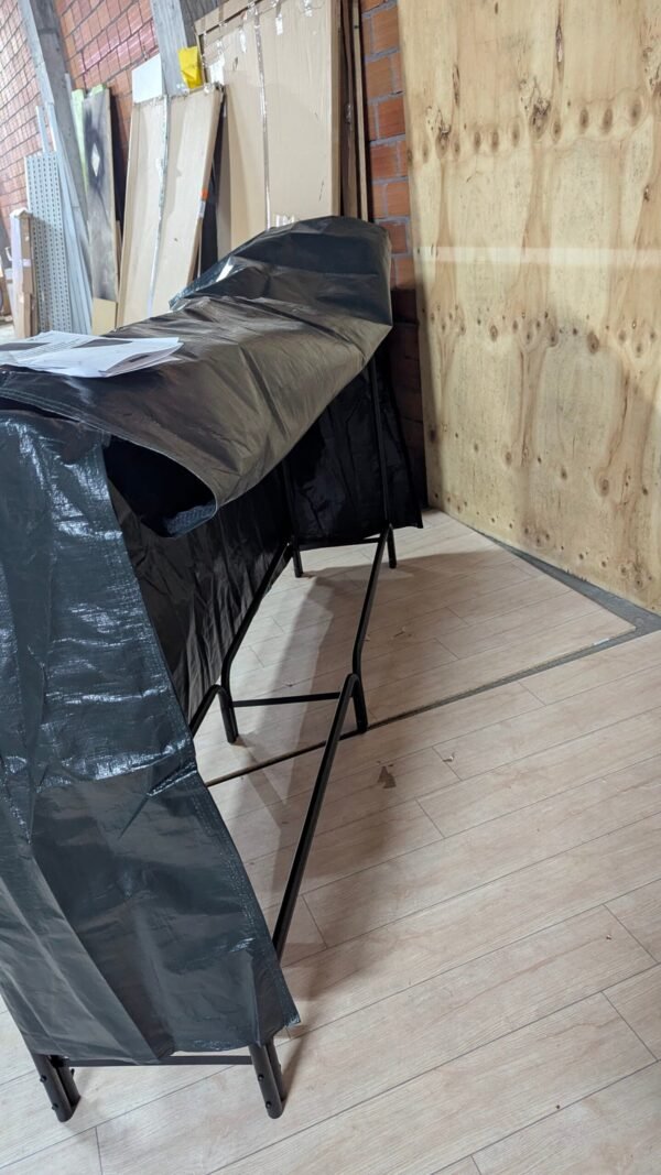 Mesa plegable cubierta por lona negra en almacén.